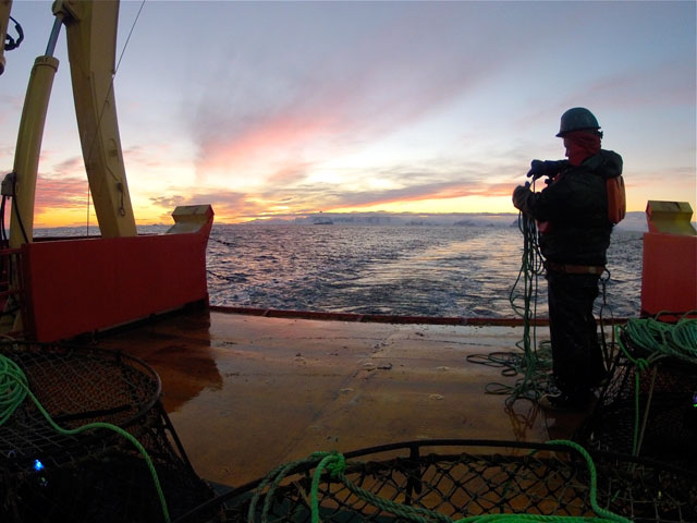 Person on deck of a ship at twilight.