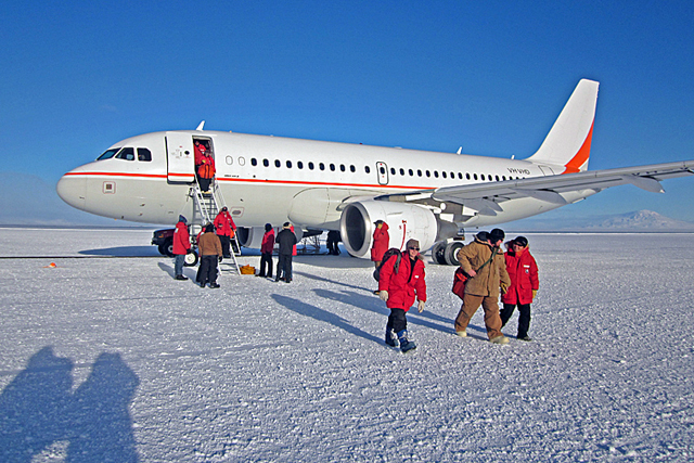 People exit plane sitting on ice.