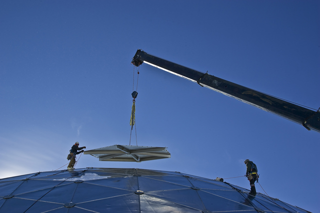 A crew member guides a section of wall off the dome.
