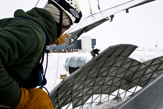 A worker helps guide a section of wall away from the dome.