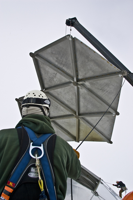 A dome panel in the air while worker watches.
