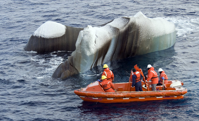 Scientists examine chunk of ice from a small boat.