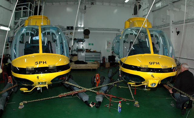 Two helicopters in a ship hangar.