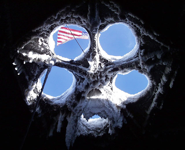 American flag seen through hole in a roof.