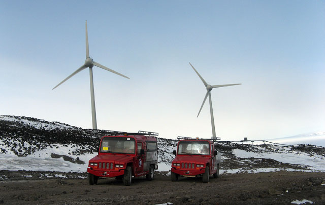 Two cars in front of turbines.