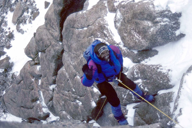 Person climbs rock face.
