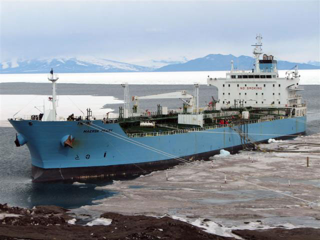 Large ship docks near slushy ice.