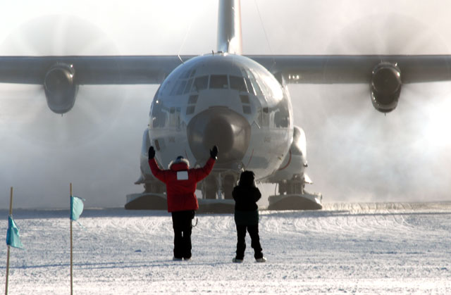 People direct an airplane on ice.