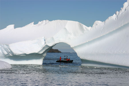 Small boat passes near iceberg.