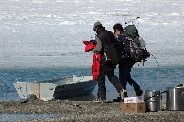 People carry equipment to small boat.