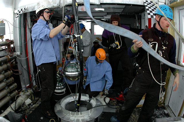 People prepare to lower instrument into a hole.