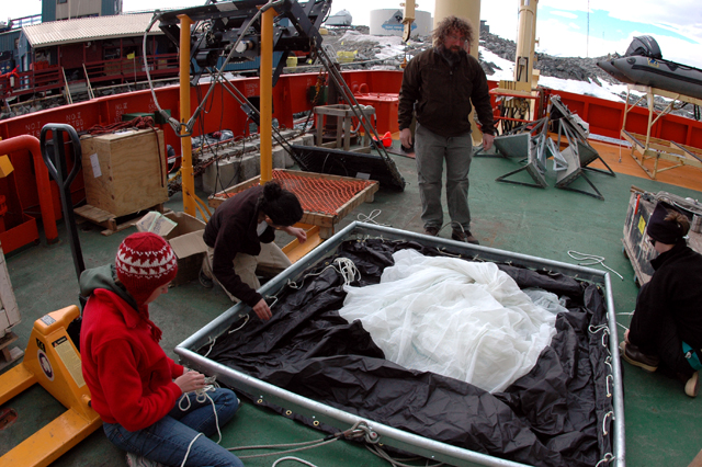 Scientists assemble net on deck of ship.