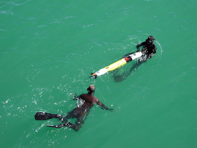 Divers in the water with an object.