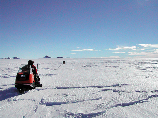 Person on snowmobile pulling an object.