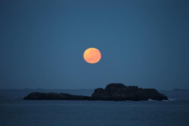 Full moon over the ocean and island.