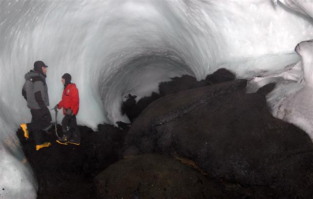 Two people stand in ice cave.