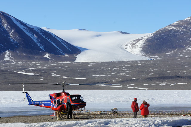 Helicopter and people in a snowy valley.