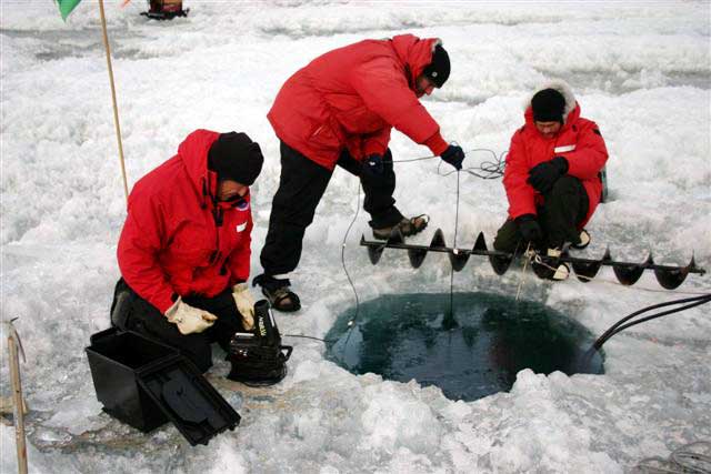 People gather around a hole in the ice.