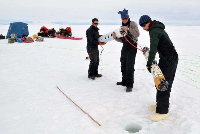 People carry instrument to an ice hole.