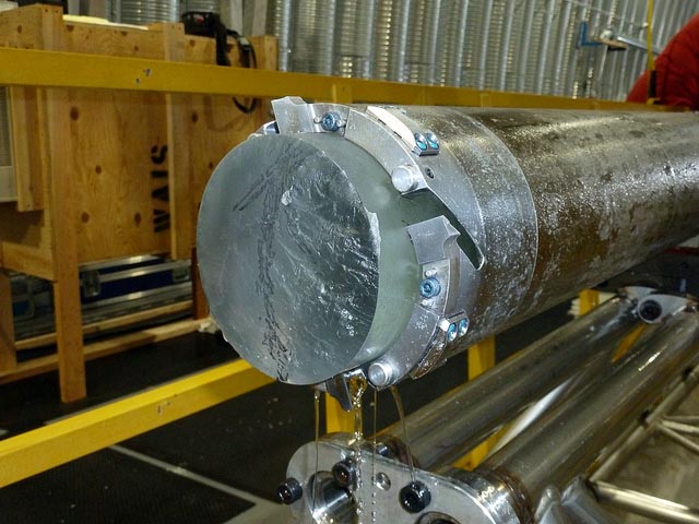 Ice core sticks out of metal barrel.