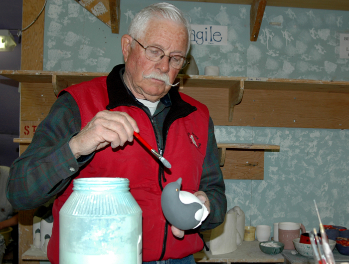 Joe Kendall paints ceramic penguin.