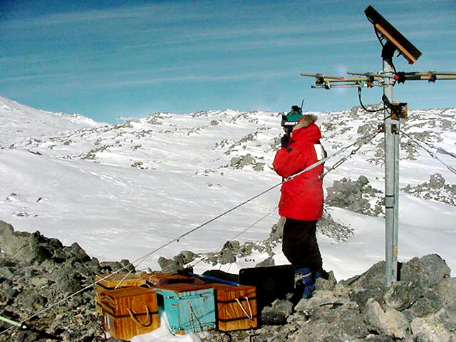 Scientist near seismometer on volcano.