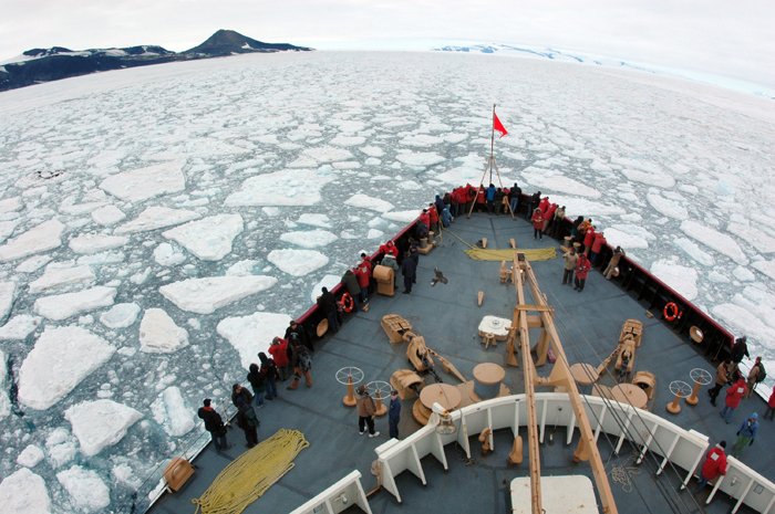Bow of vessel pushes through sea ice.