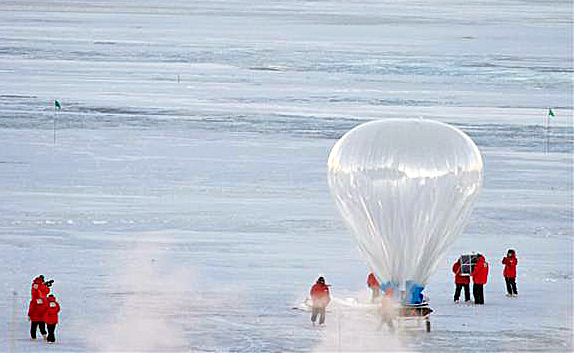 Large balloon flies above snowfield.