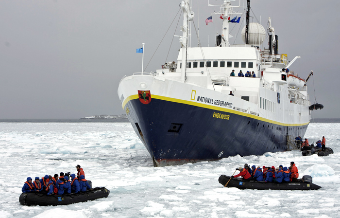 Tourists board Zodiacs from cruise ship.