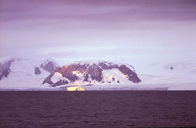Iceberg in front of mountainous island.