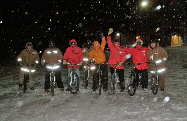 People bike at night in cold weather.