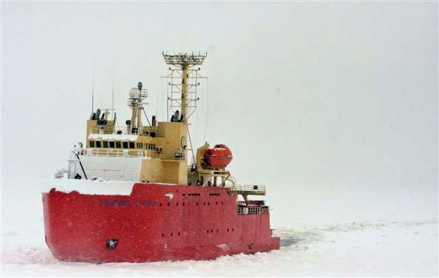 Ship sails in snowy conditions.