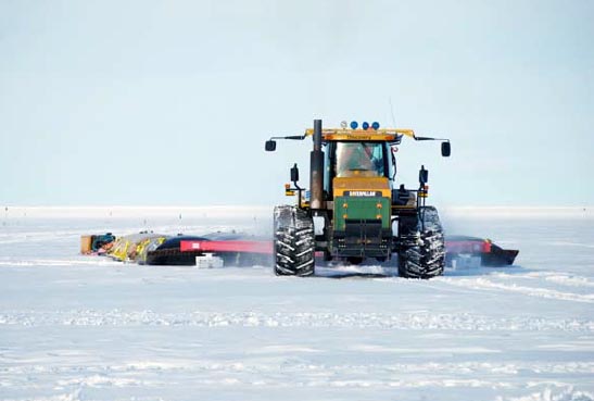 Tractors pulls a sled across snow.