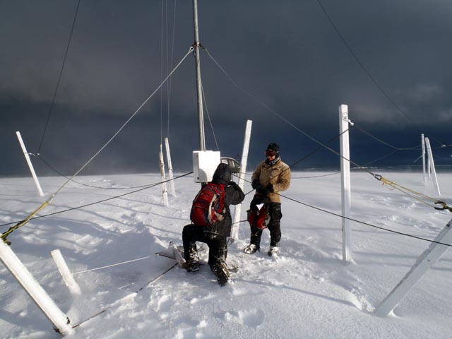 People work on an antenna in the cold.