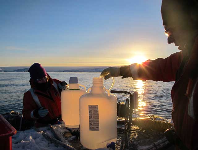 People fill jugs of water on boat.