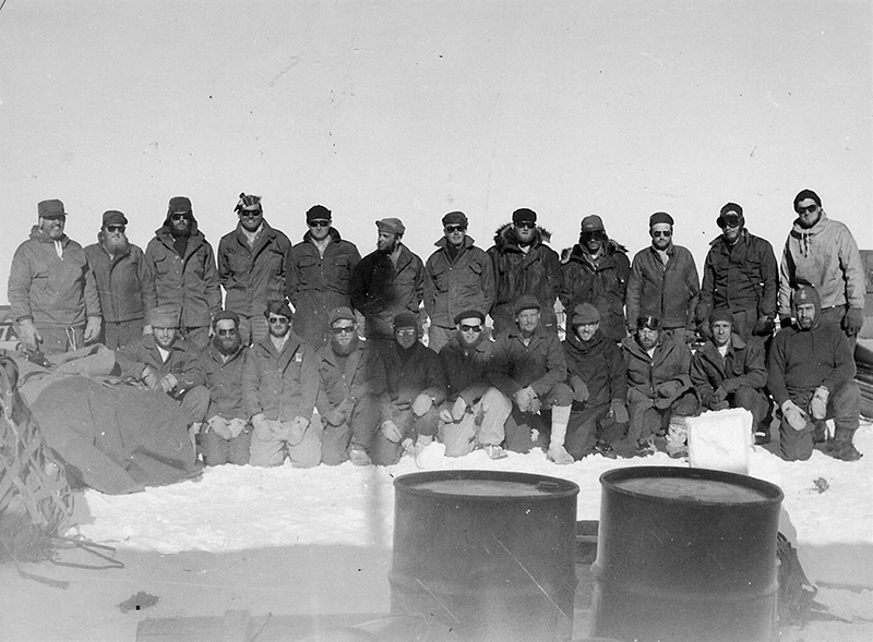 The U.S. Navy Seabees who built the first South Pole Station pose for a photo in January 1957. U.S. Navy Lieutenant (Junior Grade) Richard Bowers, leader of the team, is standing at far right, rear.