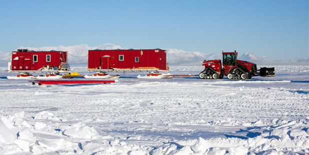 Traverse tractors pulls two buildings on sleds.