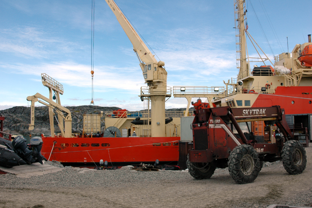 Ship crane moves container onto pier.