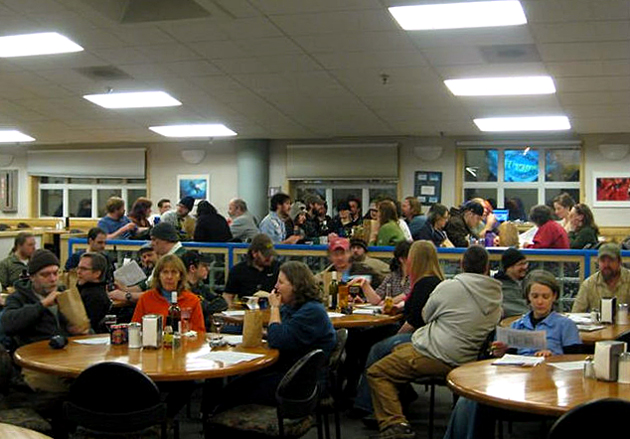 People sitting at tables in large room.