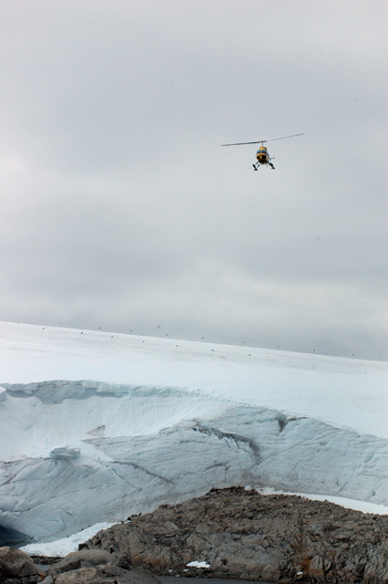 A helicopter sweeps over a glacier.