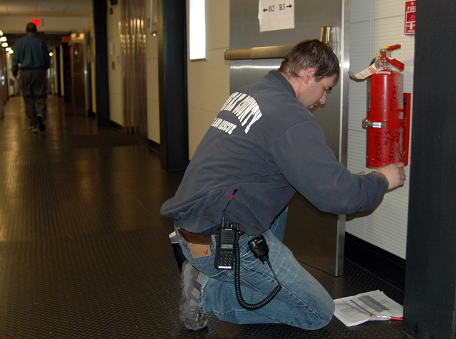 Person inspects fire extinguisher.