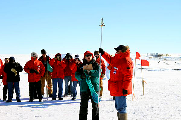 People hold up a pole marker on stick.