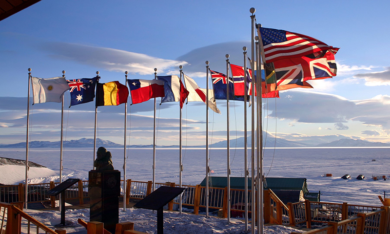 At McMurdo Station, the flags of the original 12 signatory nations to the Antarctic Treaty flap in the breeze around a bust of Admiral Richard Byrd