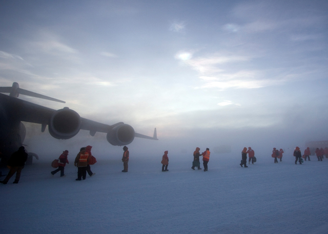 A line of passengers leaves the C-17.