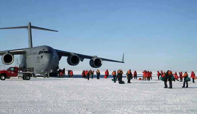 People exit a large aircraft sitting on ice.