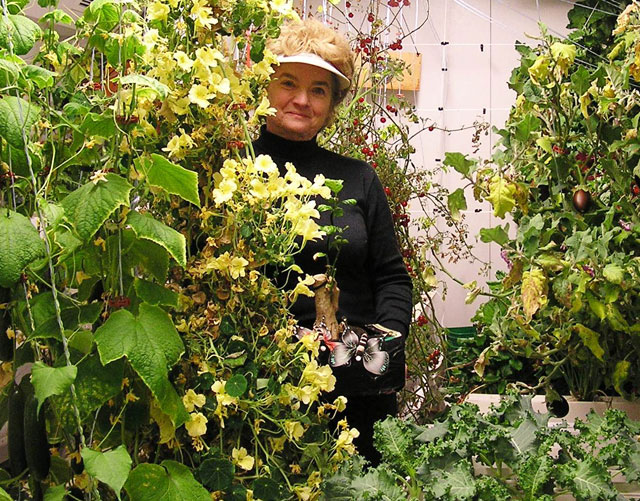 Woman stands among plants.