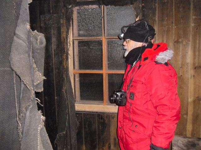 Person with headlamp inside wood building.