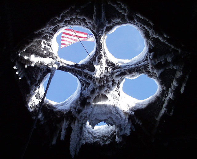 American flag flies above snow-crusted roof.