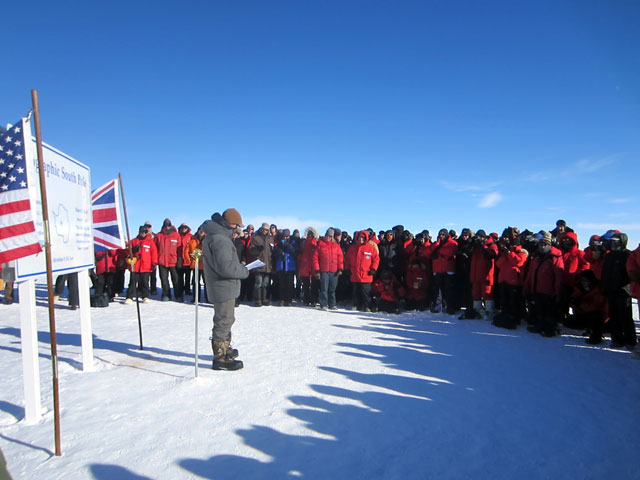 Crowd gathered around geographic South Pole and speaker.