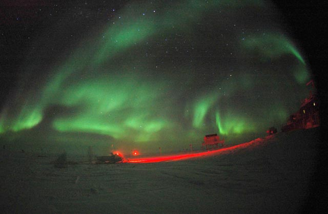 Auroras illuminate night sky.